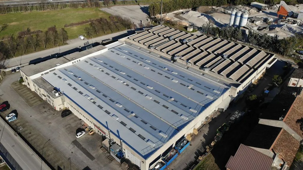 Vista aerea di una copertura industriale metallica con lucernari a nastro, affiancata a un corpo a shed